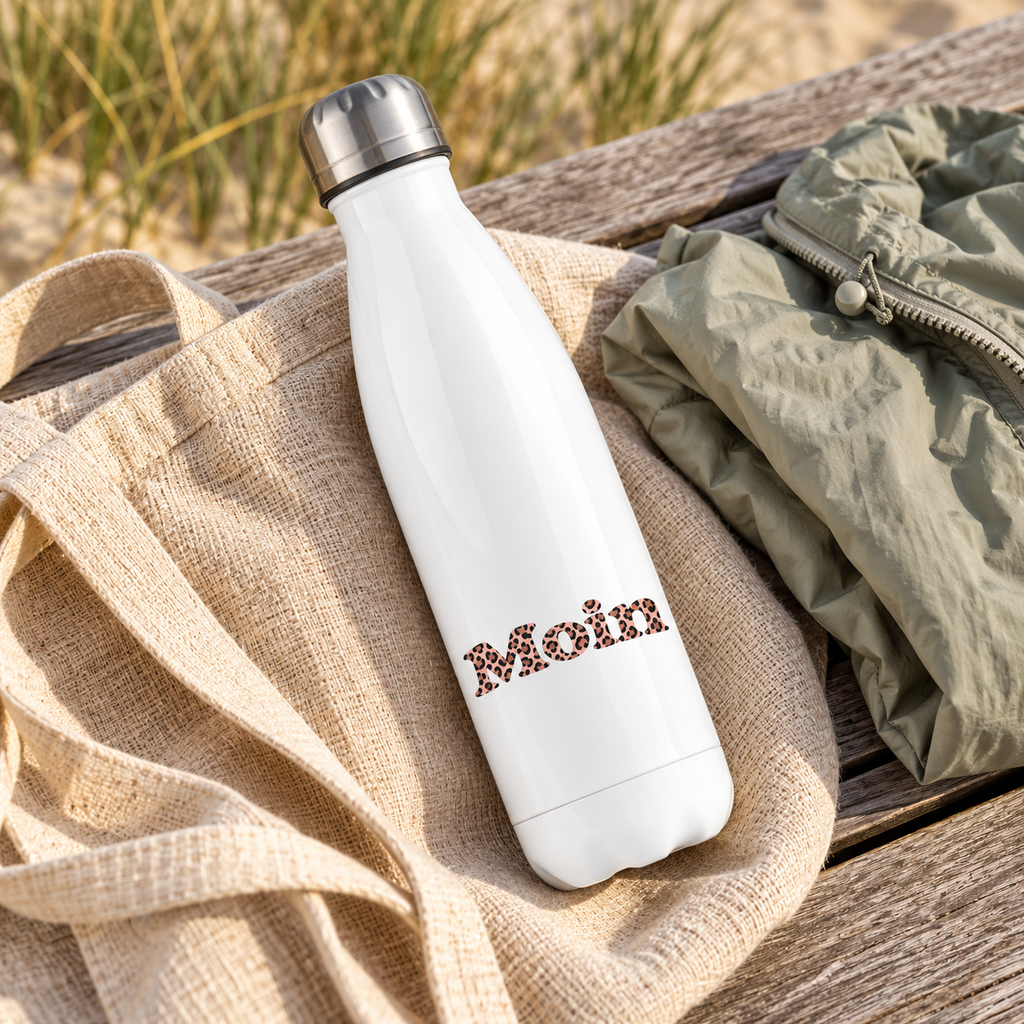 Weiße Edelstahl-Thermoflasche mit silbernem Deckel und Moin Leo Blush Pink liegt auf einer Tasche neben einer Jacke auf einer Holzbank.