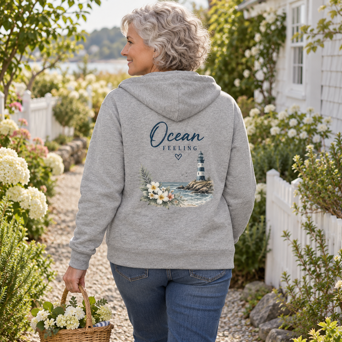 Frau im Ocean Feeling Bio-Zipper in Heather Grey mit Blumen und Leuchtturm auf dem Rücken im Garten