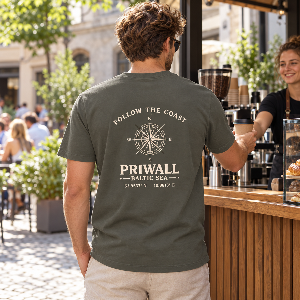 Mann im khakifarbenen Priwall Follow the Coast Bio Heavy T-Shirt mit Backprint an einem Kaffeestand