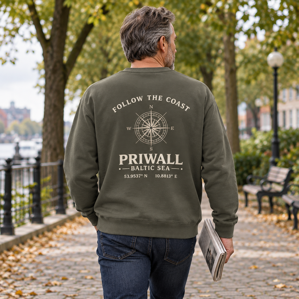 Mann im khakifarbenen Priwall Follow the Coast Bio Oversize Sweatshirt mit Rückenmotiv im Park