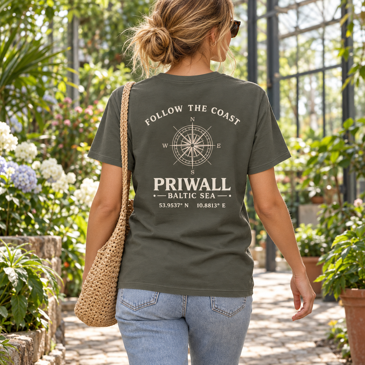Frau im khakifarbenen Priwall Follow the Coast Bio T-Shirt mit Backprint im botanischen Garten