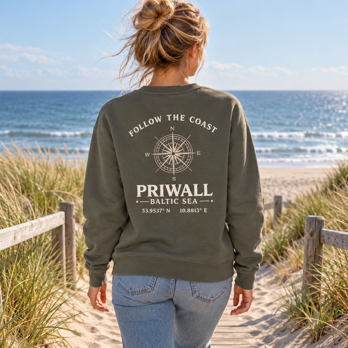 Frau im grauen Priwall Follow the Coast Bio Unisex Sweatshirt mit Rückenmotiv am Ostseestrand