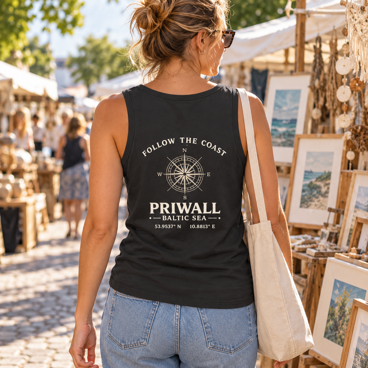 Frau im schwarzen Priwall Follow the Coast Damen Bio Fitted Tank Top mit Rückenmotiv auf einem Kunstmarkt