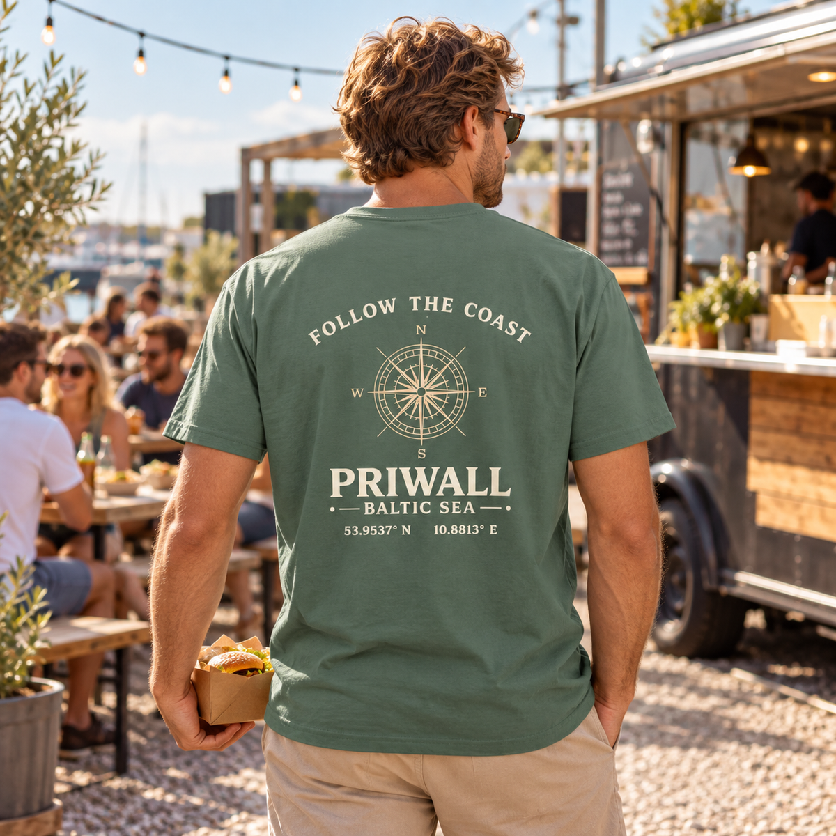 Mann im grünen Priwall Follow the Coast Essential T-Shirt mit Backprint in einem Food-Truck-Hof
