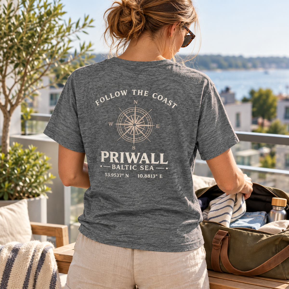 Frau im grauen Priwall Follow the Coast Essential T-Shirt mit Rückenmotiv beim Packen für einen Wochenendtrip