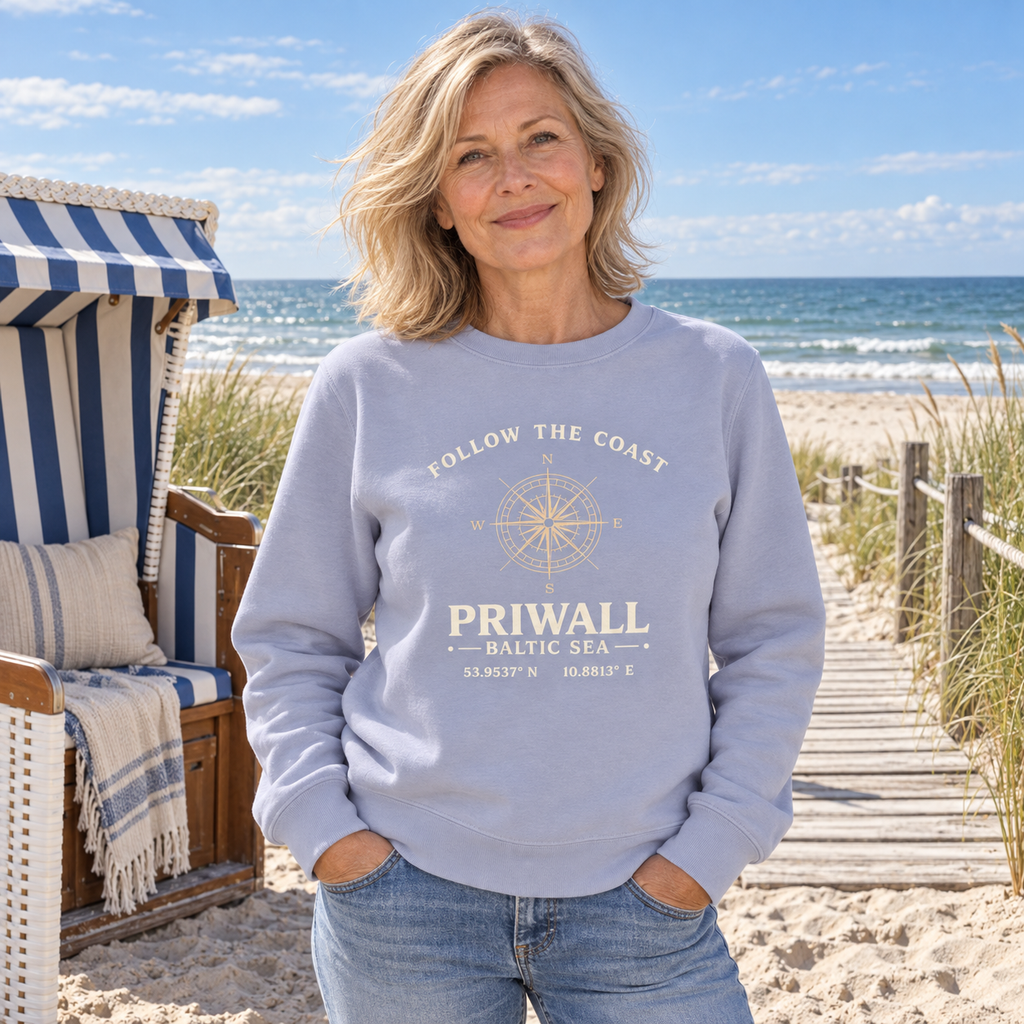Frau trägt hellblaues Priwall Follow the Coast Bio-Sweatshirt am Strandkorb