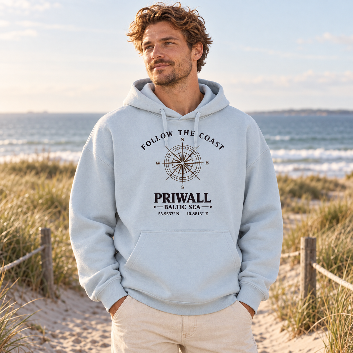 Mann trägt den Priwall Follow the Coast Oversize Bio-Hoodie in Blue Ice am Ostseestrand