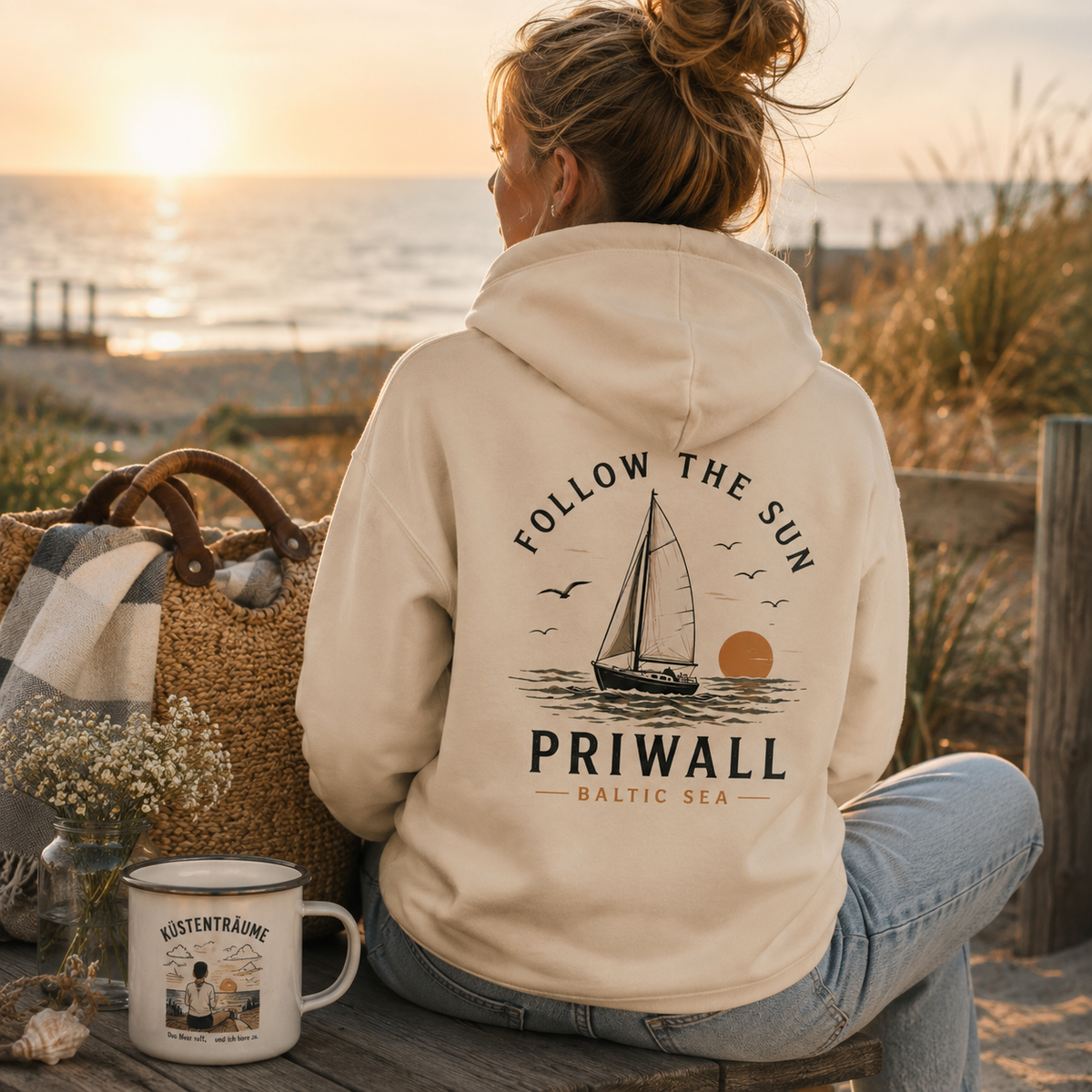 Frau im Natural Raw Priwall Follow the Sun Bio-Hoodie mit Rückenprint in einer Küstenszene