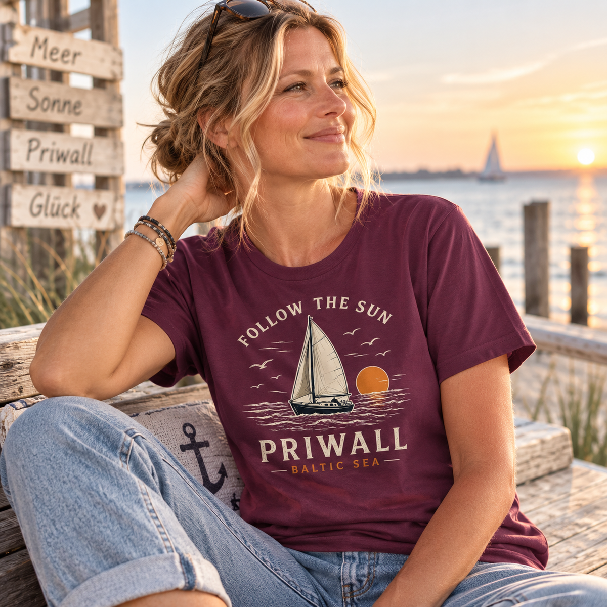 Frau mittleren Alters im burgunderroten Priwall Follow the Sun T-Shirt von Nomavé am Wasser bei Sonnenuntergang