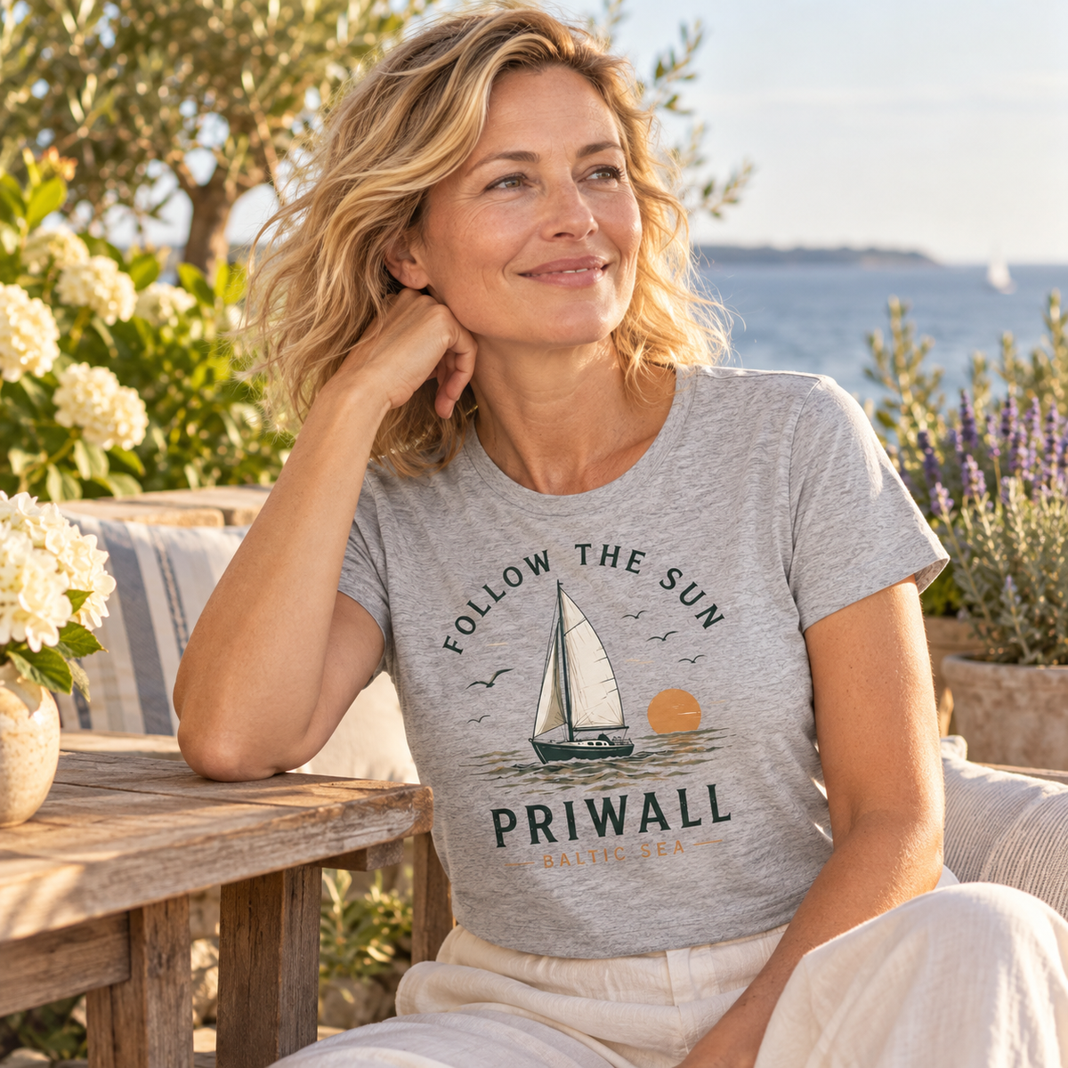 Frau im Heather Grey Priwall Follow the Sun Damen-Bio-T-Shirt auf einer Küstenterrasse