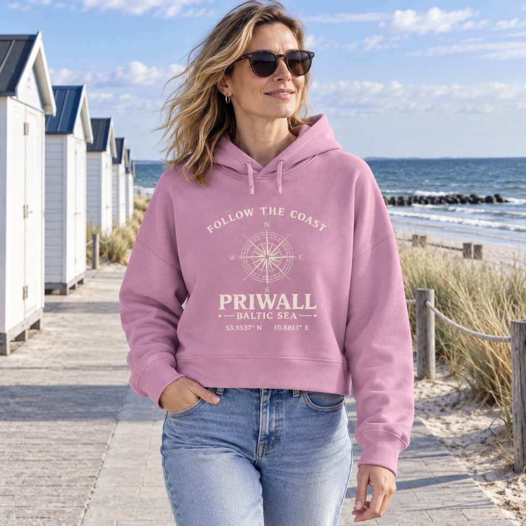 Frau trägt Priwall Kompass Dark Edition Damen Boxcut Hoodie in Bubble Pink an der Ostsee