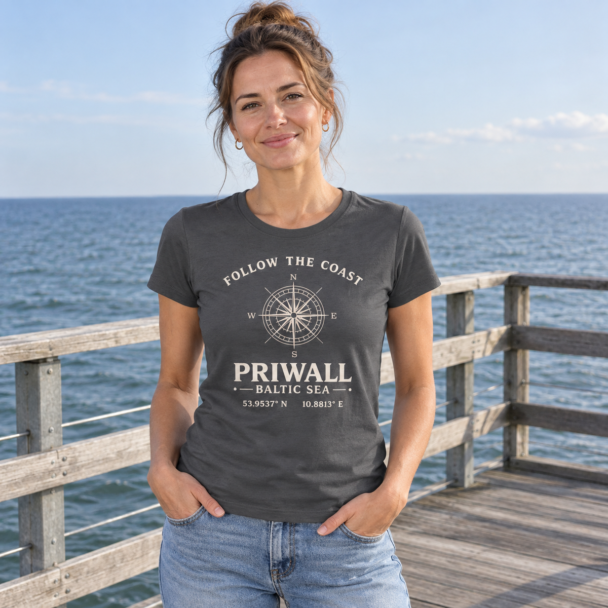Frau trägt Priwall Kompass Dark Edition Ladies Organic Shirt in Anthracite auf einem Küstensteg