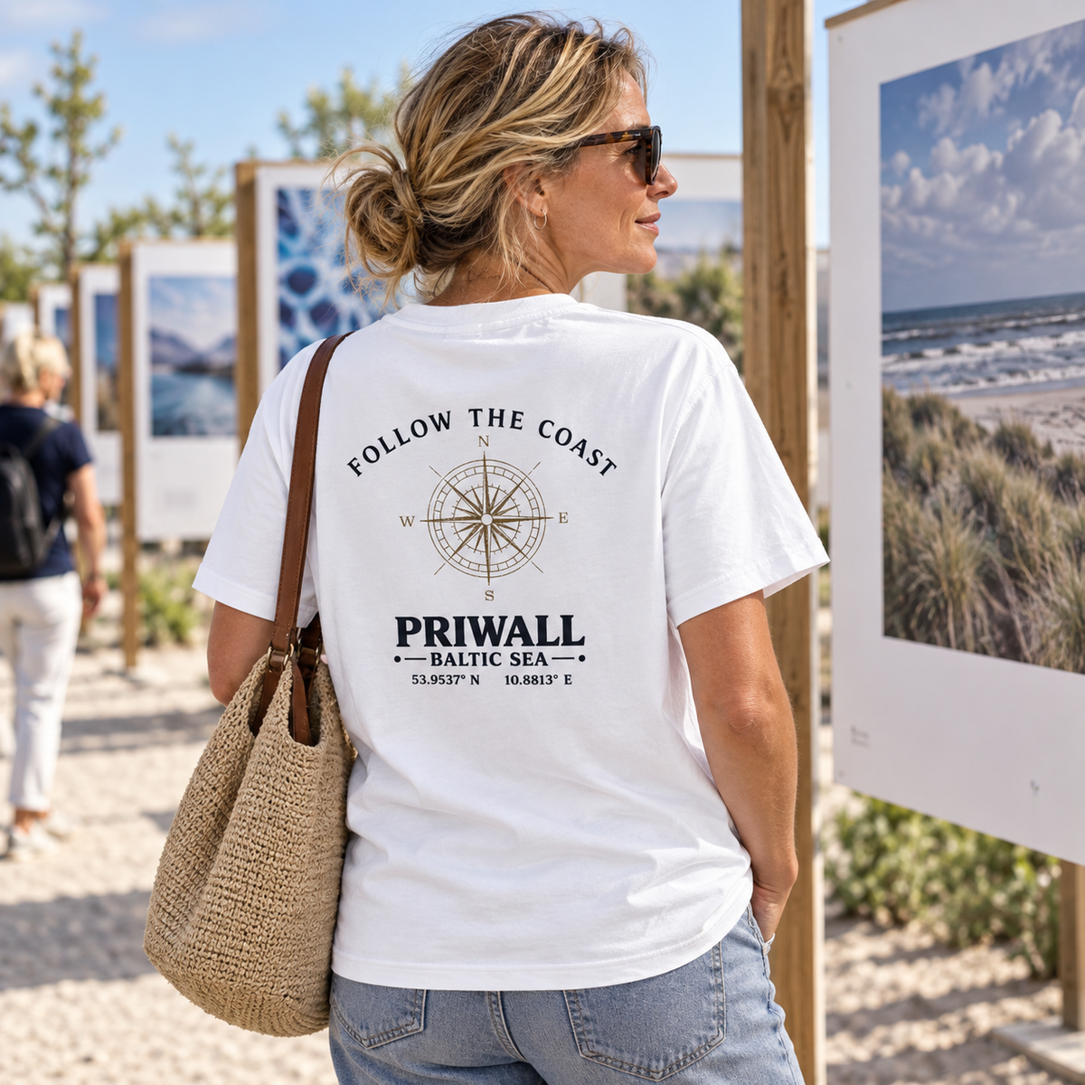 Frau im Bio Heavy T-Shirt mit hellem Follow the Coast Rückenmotiv bei einer Kunstausstellung