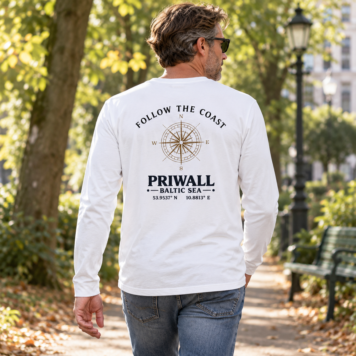Mann im Bio Longsleeve mit hellem Priwall Follow the Coast Backprint bei einem Parkspaziergang