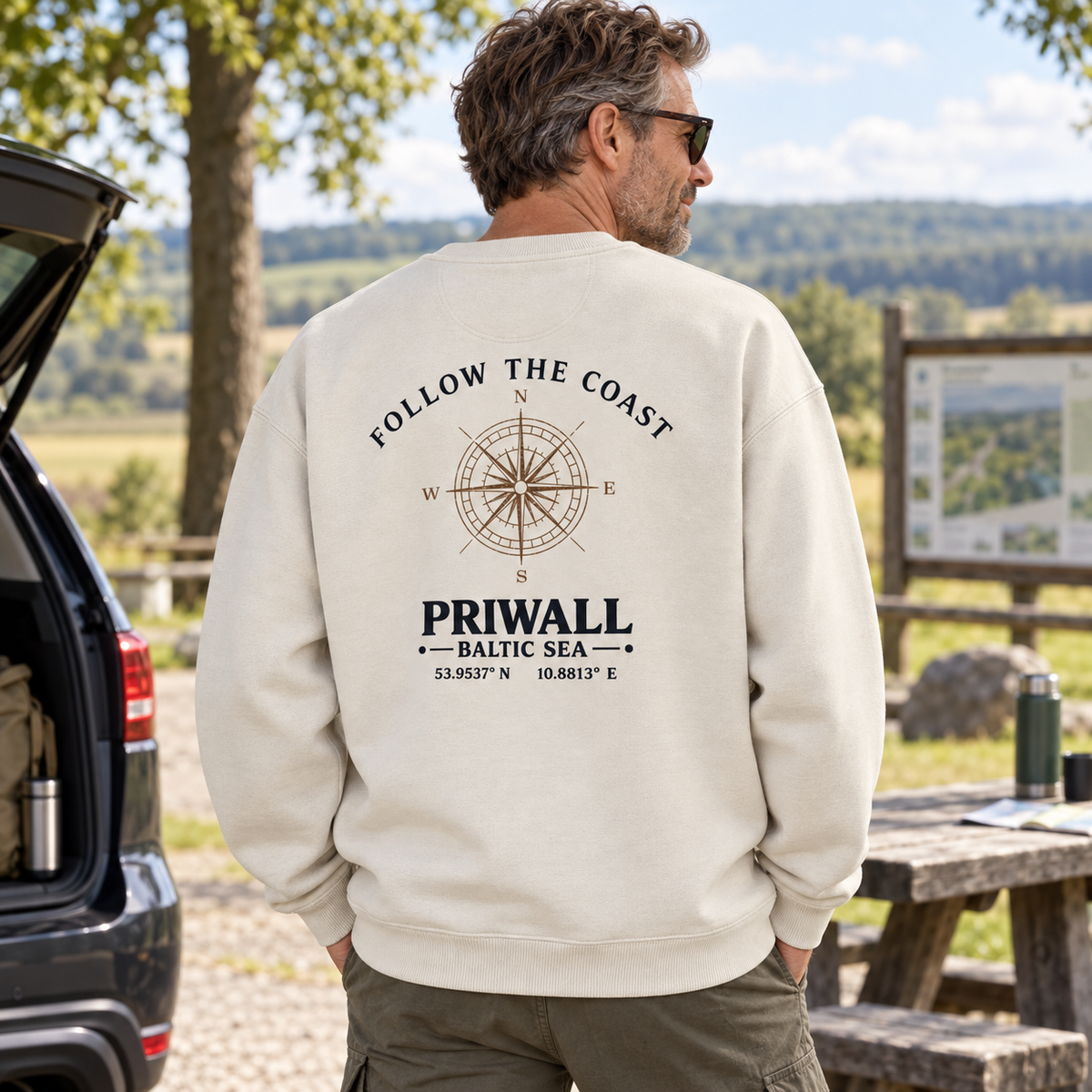 Mann im Bio Oversize Sweatshirt mit hellem Follow the Coast Backprint bei einer Reisepause