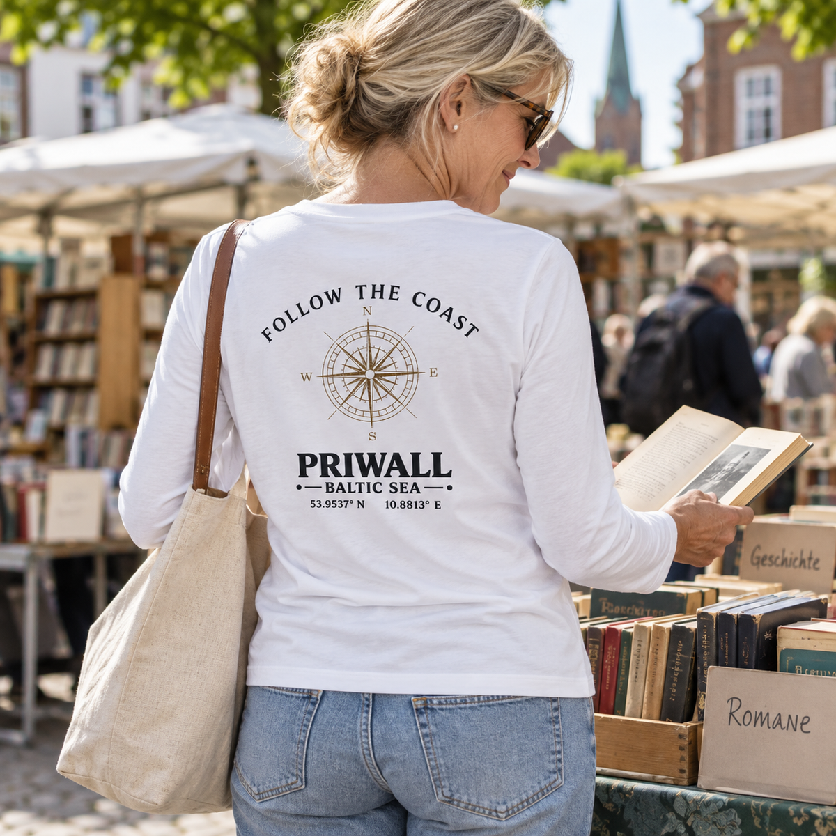 Frau im Damen Bio Longsleeve mit hellem Follow the Coast Rückenmotiv auf einem Büchermarkt