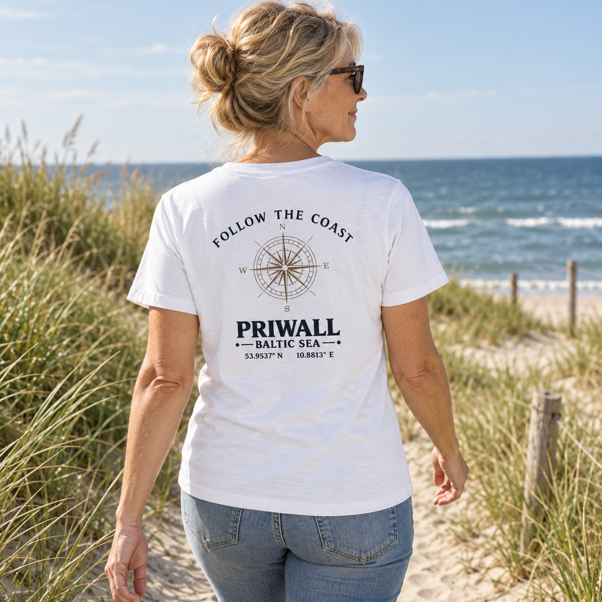 Frau im Damen Bio T-Shirt mit hellem Follow the Coast Rückenmotiv an der Ostseeküste
