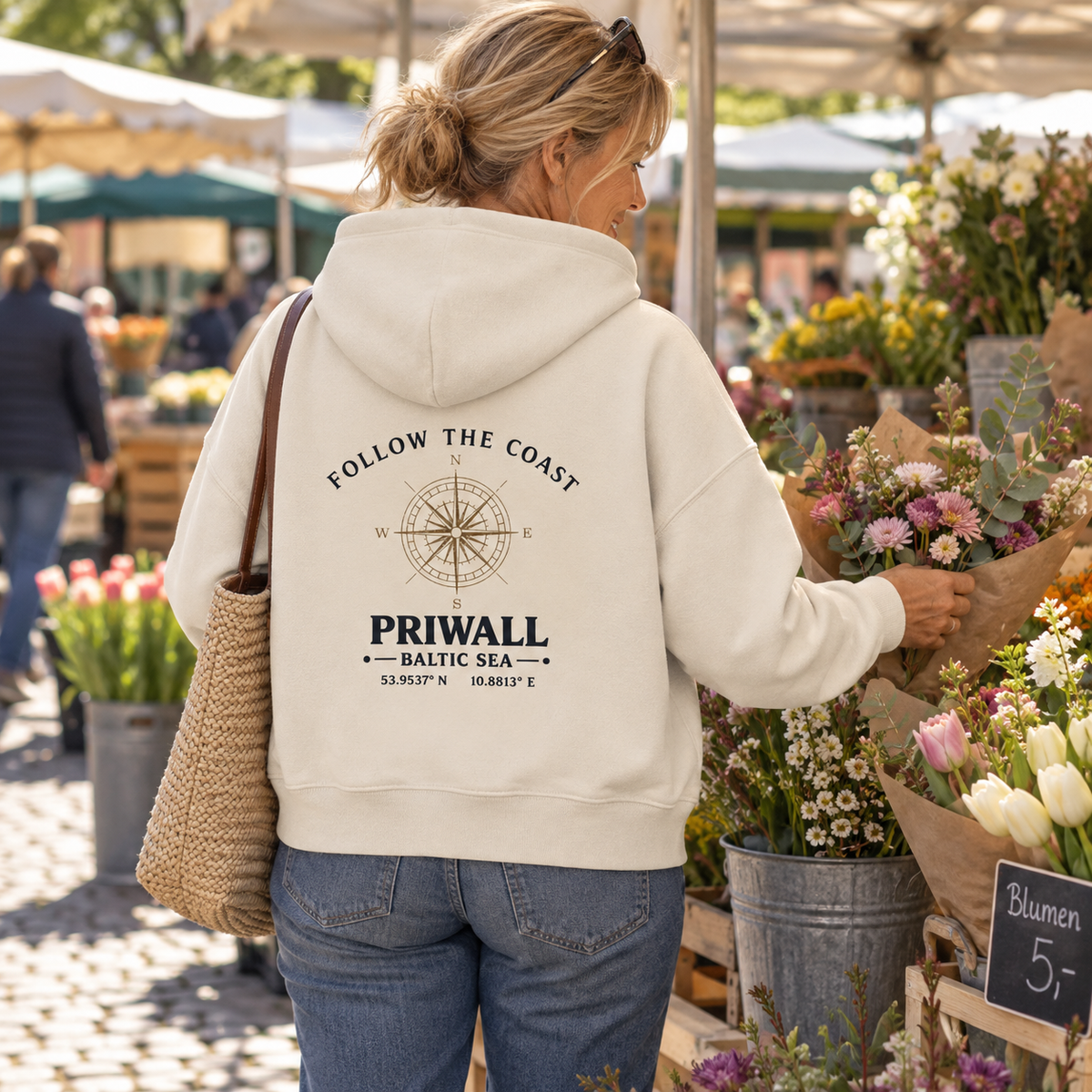 Frau im Bio Boxcut Hoodie mit hellem Priwall Backprint auf einem Blumenmarkt