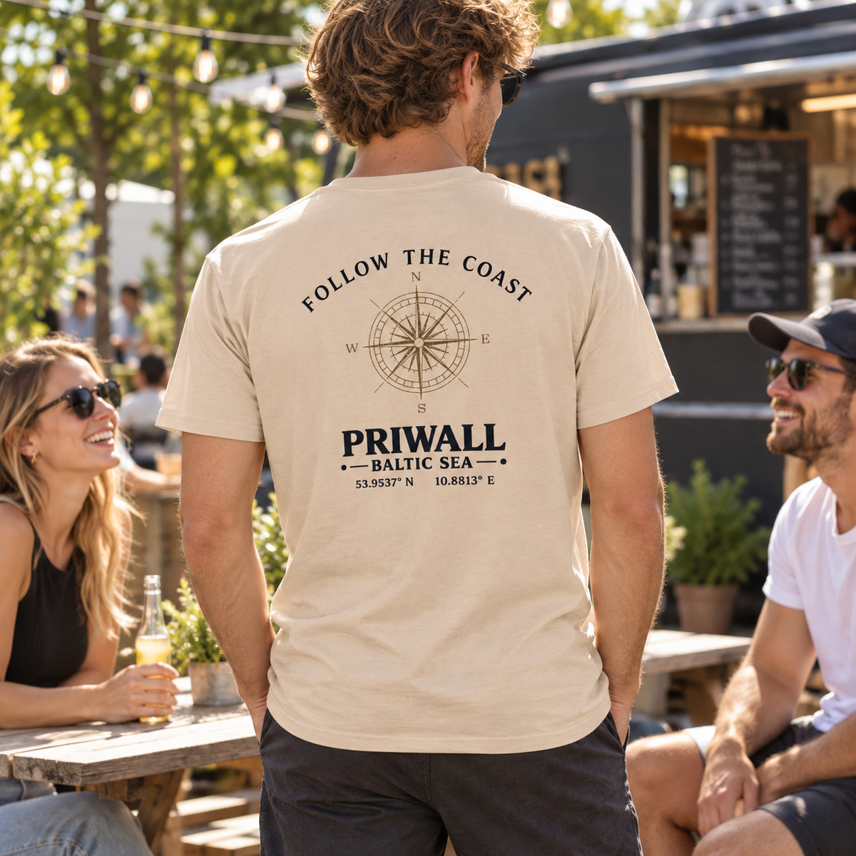 Mann im Essential T-Shirt mit hellem Priwall Follow the Coast Backprint bei einem Treffen mit Freunden