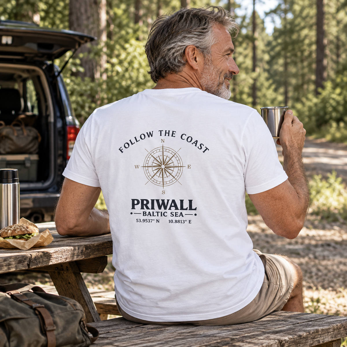 Mann im Bio V-Ausschnitt T-Shirt mit hellem Follow the Coast Rückenmotiv bei einer Roadtrip-Pause