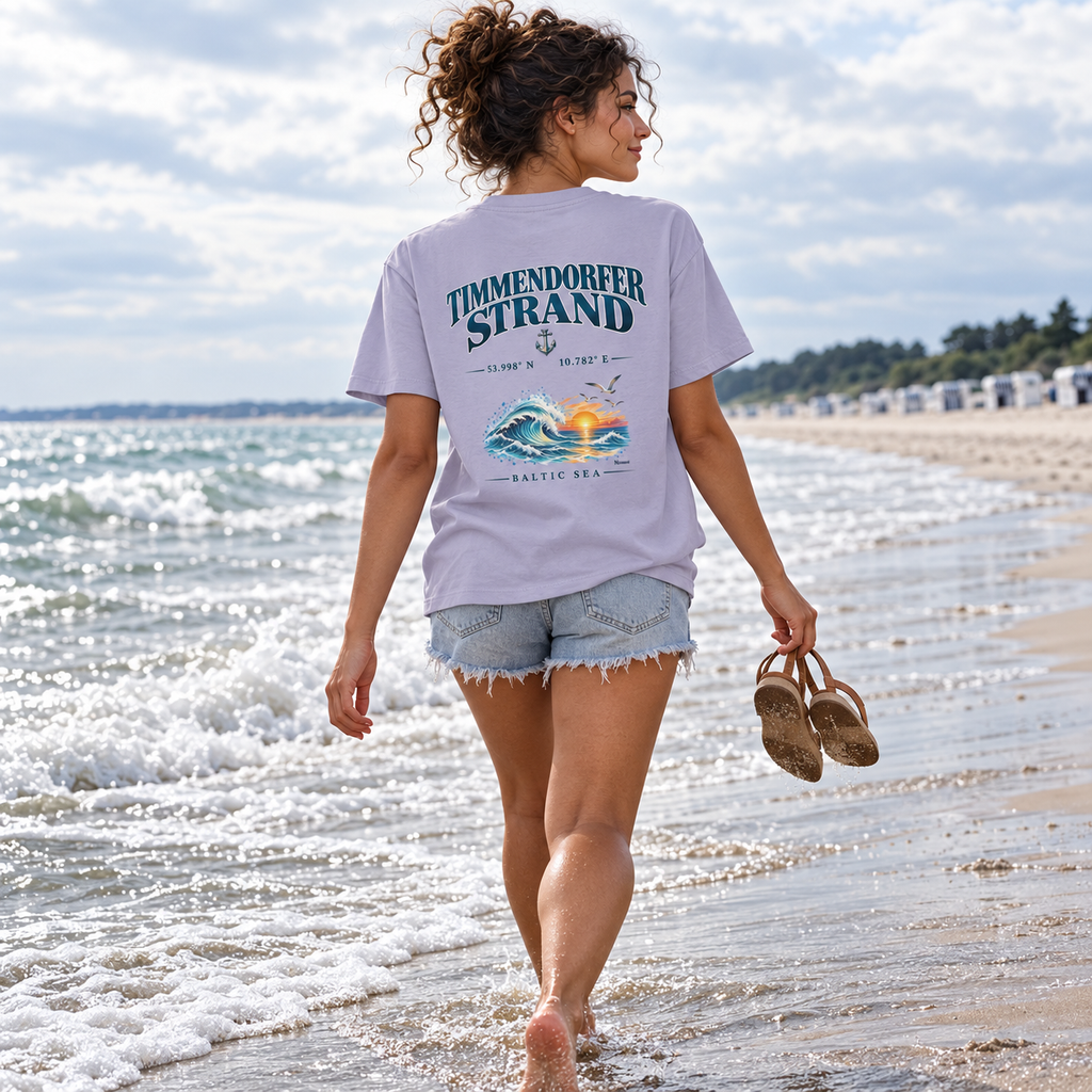 Frau im Damen Bio-T-Shirt in Lavender mit Baltic Sea Backprint beim barfüßigen Spaziergang an der Ostsee.