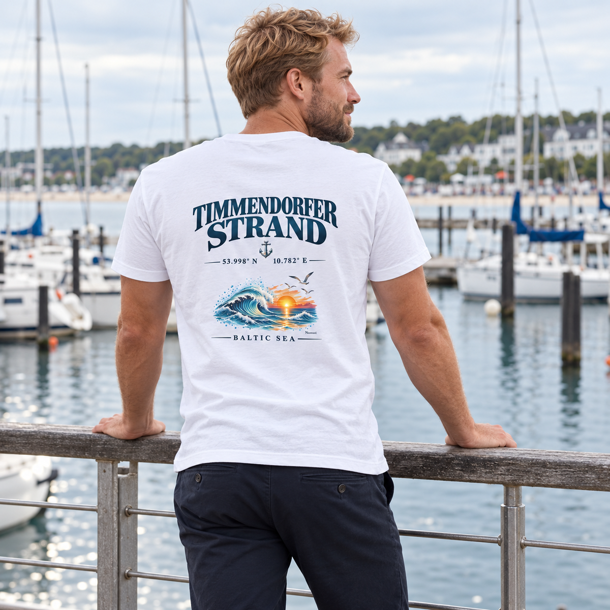 Mann im weißen Herren Bio-V-Neck-T-Shirt mit Timmendorfer Strand – Baltic Sea Rückenprint an einer Marina.