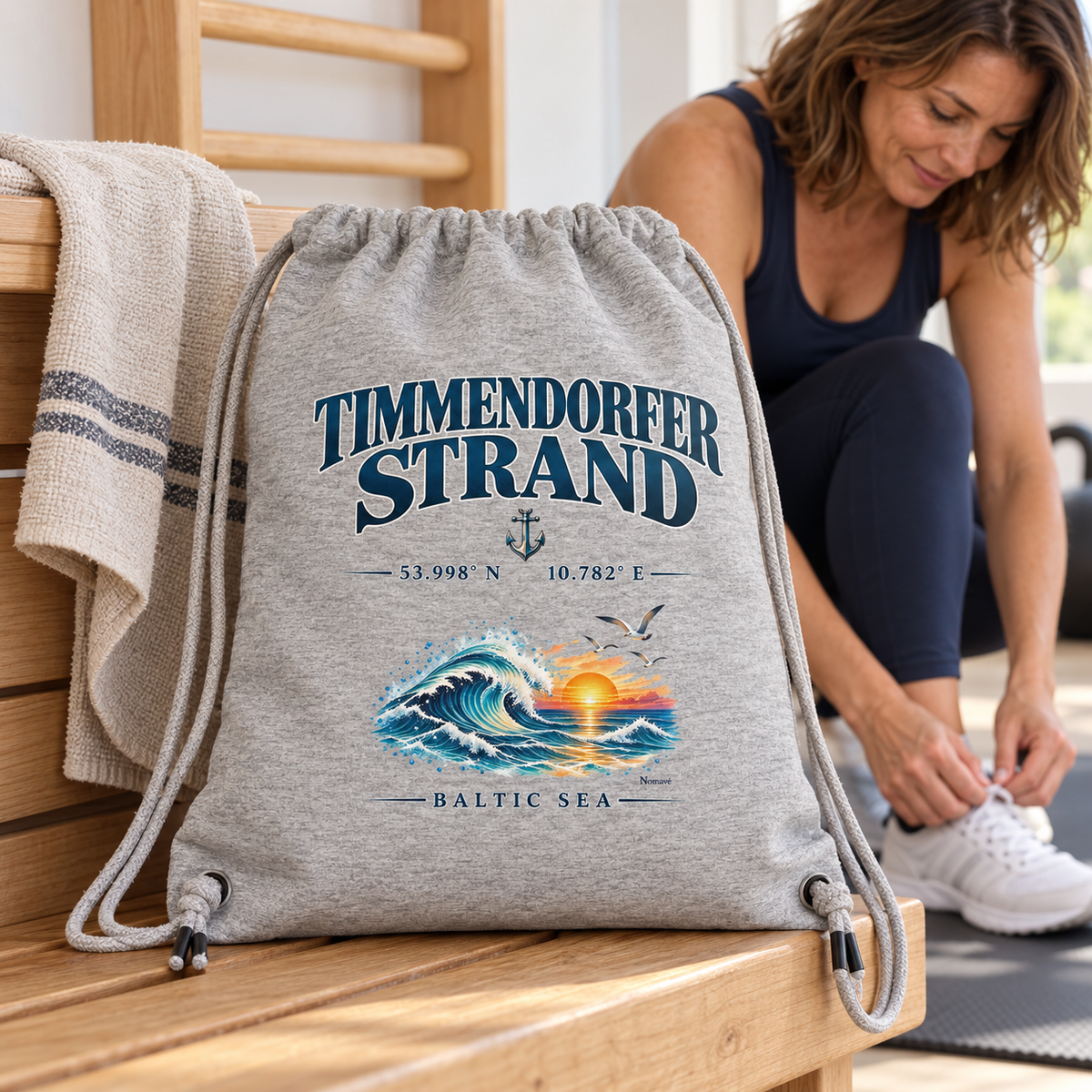 Gym-Bag Rucksack in Heather Grey mit Timmendorfer-Strand–Baltic-Sea-Frontmotiv: Beutel steht auf einer Holzbank im hellen Fitnessraum, dahinter bindet eine Frau ihre Schuhe.