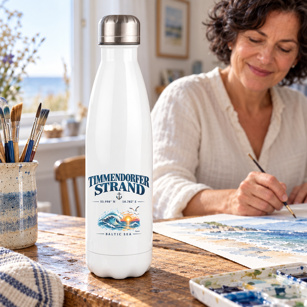 Thermoflasche 500 ml in Weiß mit Silberdeckel und Timmendorfer-Strand–Baltic-Sea-Motiv im unteren Flaschenbereich: Flasche steht am kreativen Arbeitsplatz einer Frau, die ein Küstenaquarell malt.