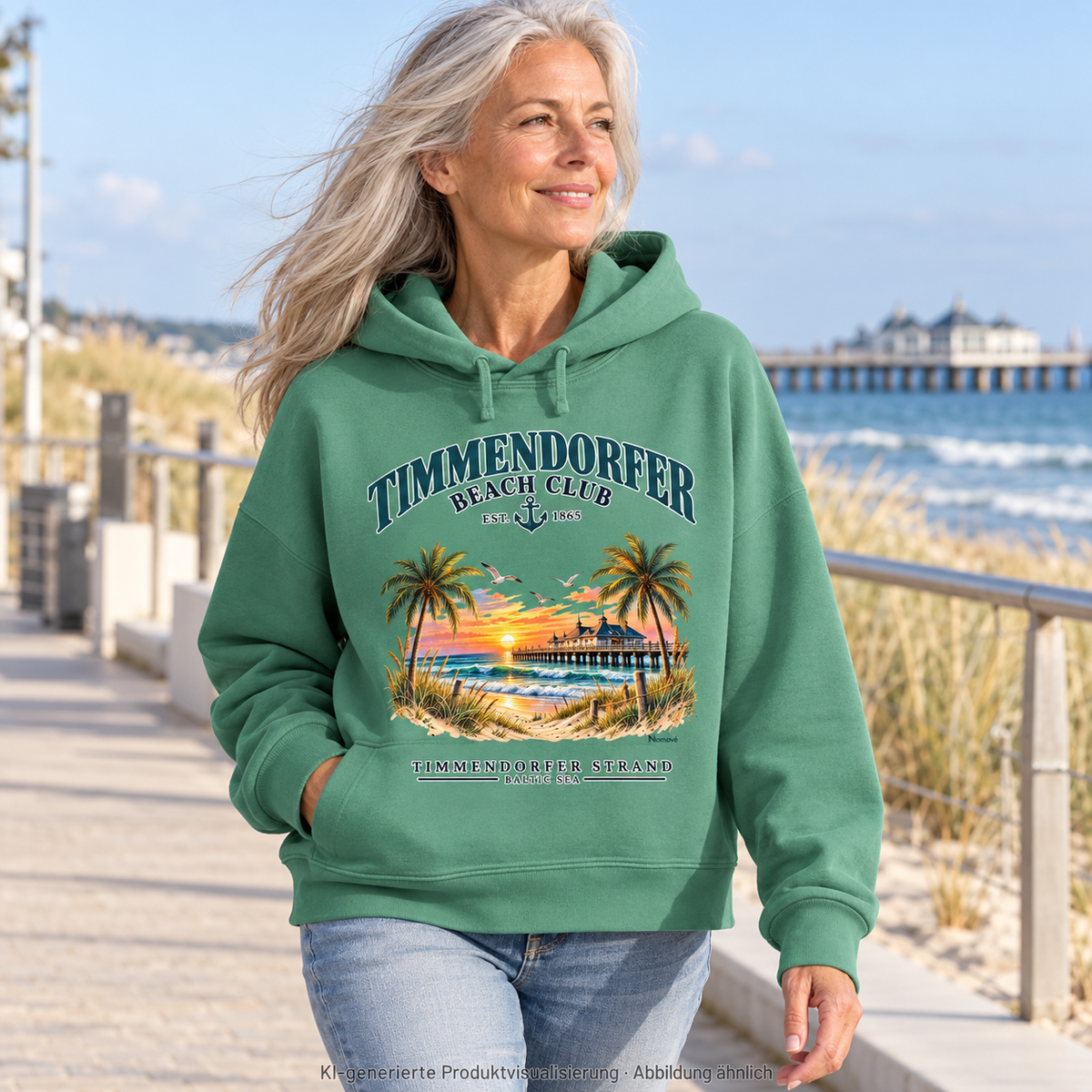 KI-generierte Produktvisualisierung: Frau auf einer Promenade im Timmendorfer Beach Club Damen Bio-Boxcut-Hoodie in Green Bay mit maritimem Frontprint.