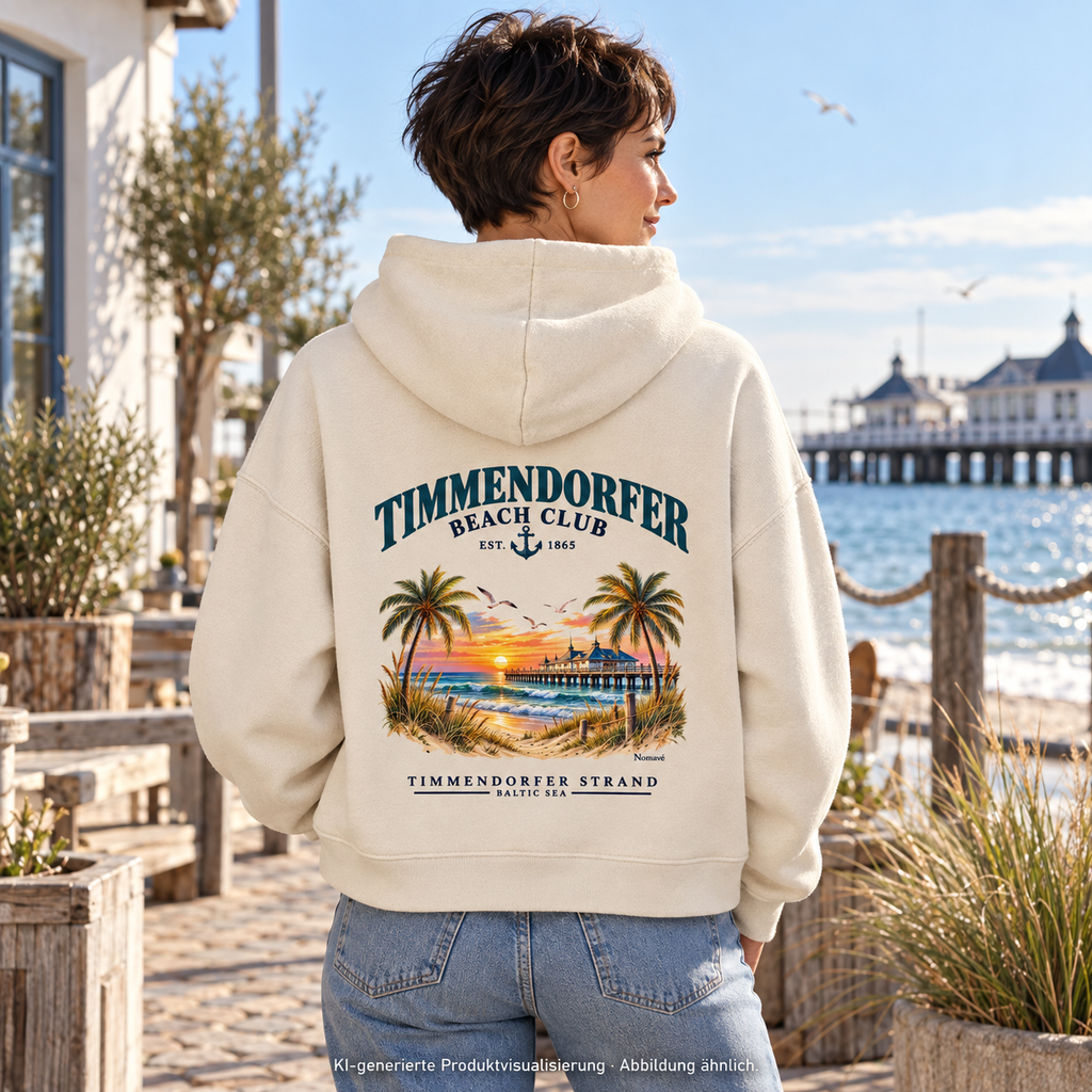 KI-generierte Produktvisualisierung: Frau im Damen Bio-Boxcut-Hoodie Natural Raw mit Timmendorfer-Beach-Club-Rückendruck in einem maritimen Hof.