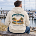 KI-generierte Produktvisualisierung: Mann im Bio-Oversize-Hoodie Natural Raw mit Timmendorfer-Beach-Club-Rückendruck auf einer Marinabank.