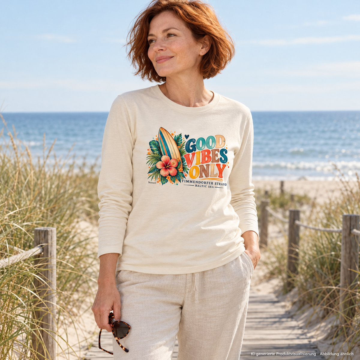 KI-generierte Produktvisualisierung: Frau im Natural-Raw Bio-Langarmshirt mit Surf-Vibes-Frontprint aus Surfboard, Hibiskus und Good Vibes Only am Ostsee-Strandzugang.