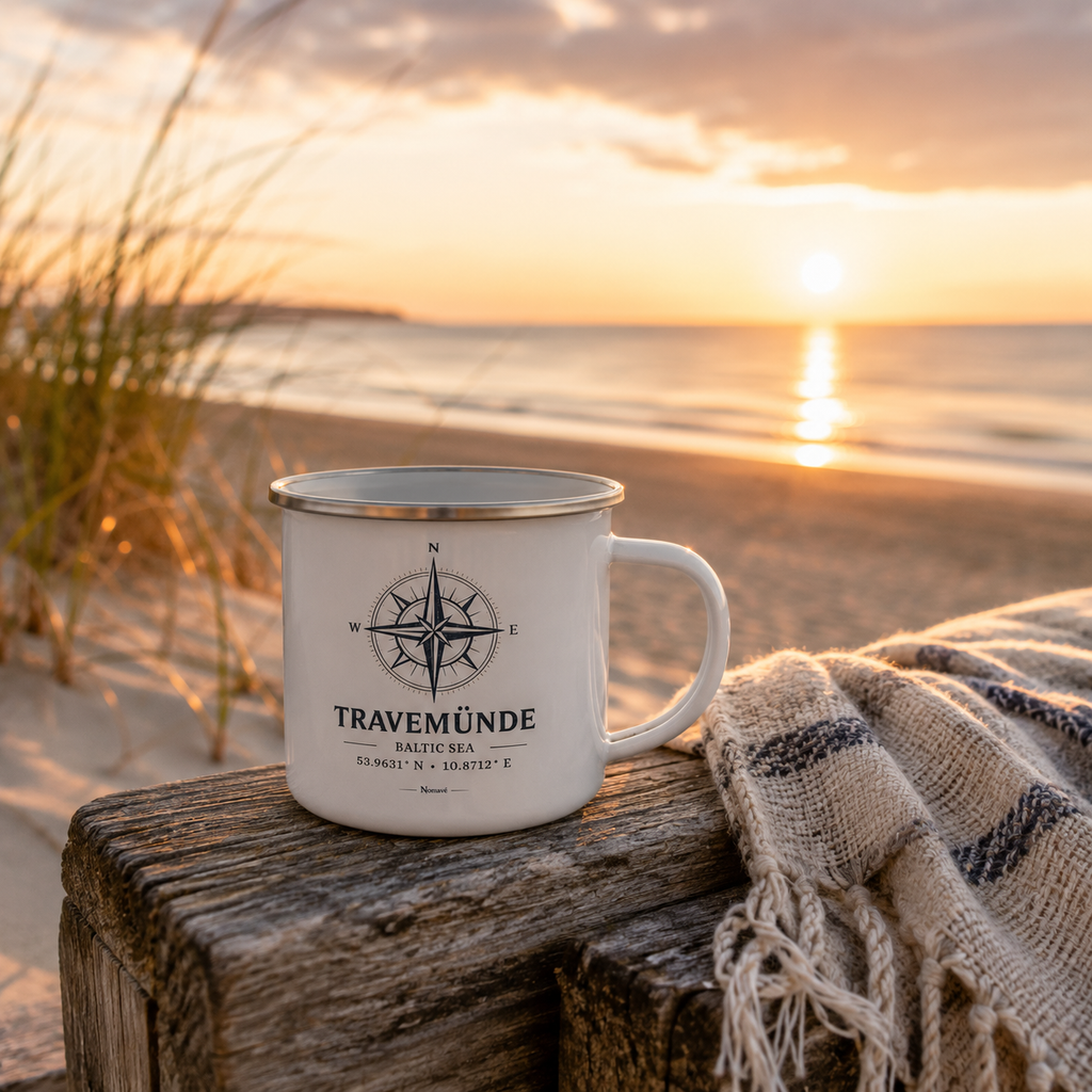 Weißer Emaillebecher mit silbernem Rand und maritimem Kompassmotiv „Travemünde Baltic Sea“ von Nomavé auf einem verwitterten Holzpfosten am Ostseestrand im goldenen Morgenlicht. Eine weiche Decke, Dünen und der ruhige Sonnenaufgang über dem Meer schaffen eine warme Küstenatmosphäre und machen den leichten Campingbecher zum perfekten Begleiter für Kaffee oder Tee am Strand.