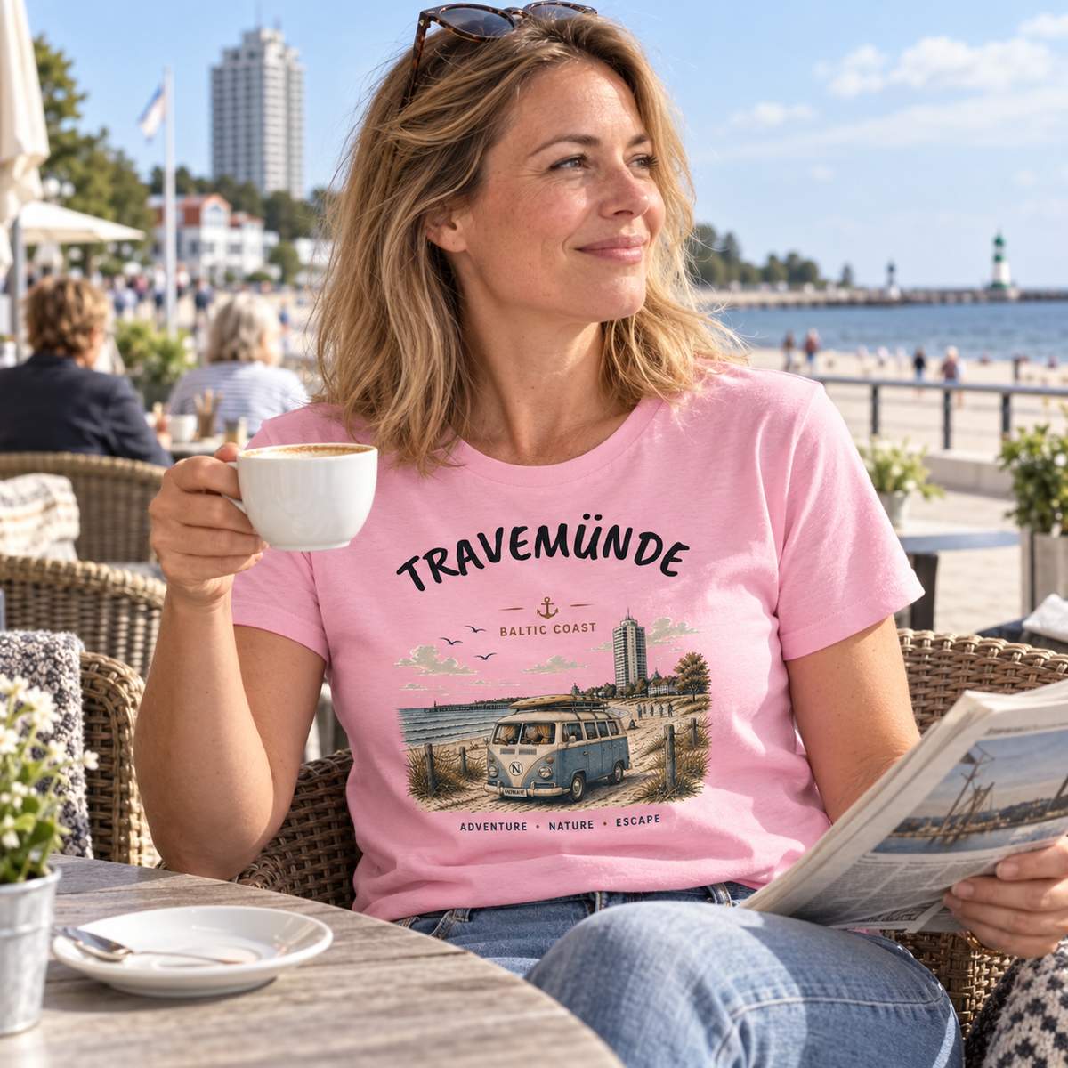 Frau im pinken Travemünde Bulli Bio T-Shirt im Café an der Ostseepromenade