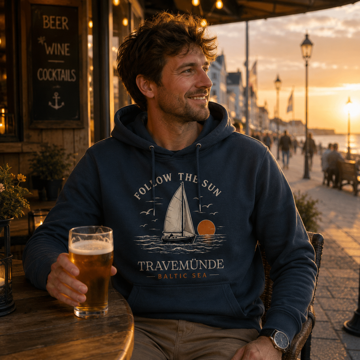 Mann trägt Travemünde Follow The Sun Dark Edition Hoodie an der Ostsee