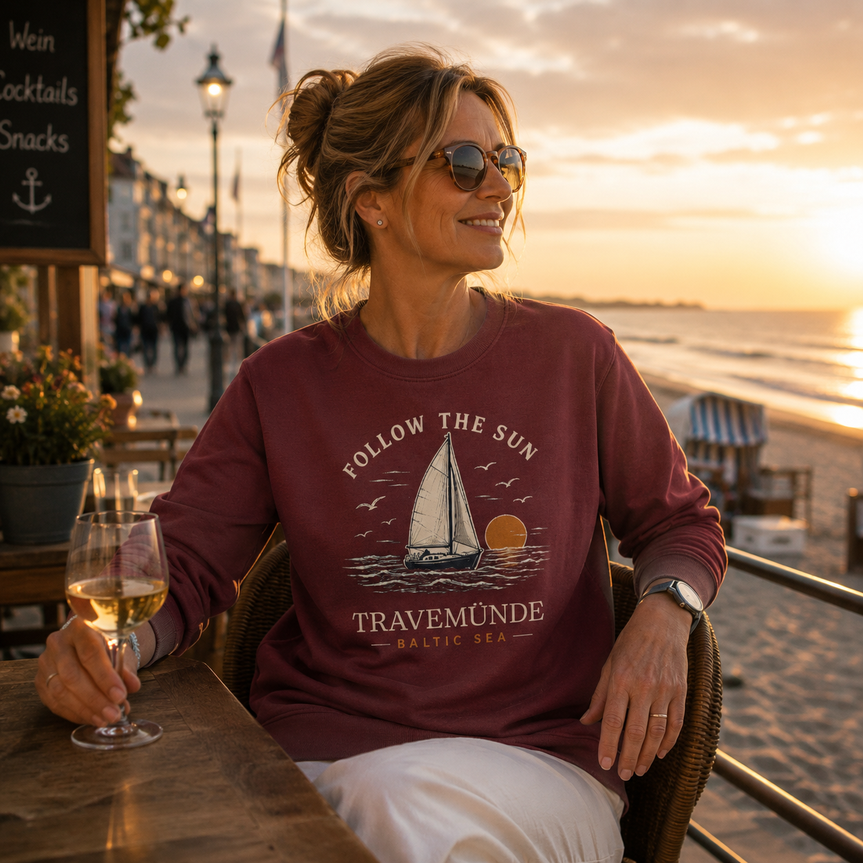 Frau trägt Travemünde Follow The Sun Dark Edition Sweatshirt bei Sonnenuntergang in Travemünde