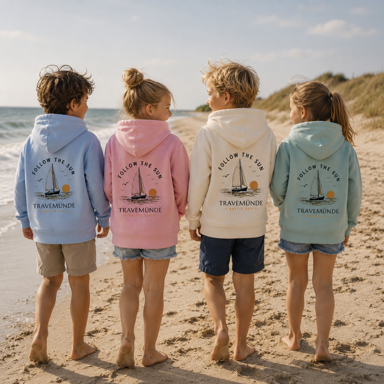 Kinder am Strand mit Travemünde Follow the Sun Hoodie und Segelboot Motiv