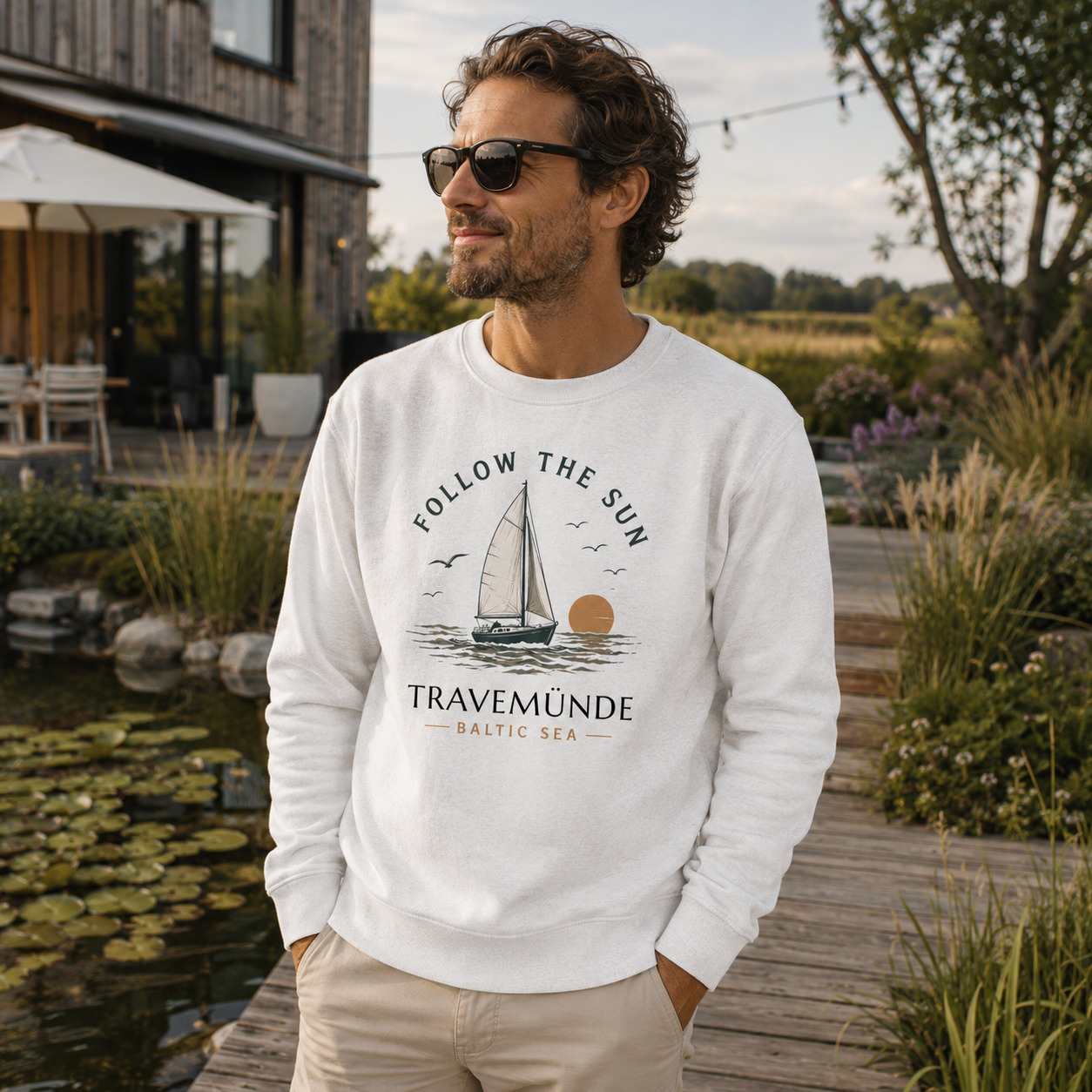 Mann trägt Follow the Sun Sweatshirt in dem Garten eines Hotels in Travemünde an der Ostsee