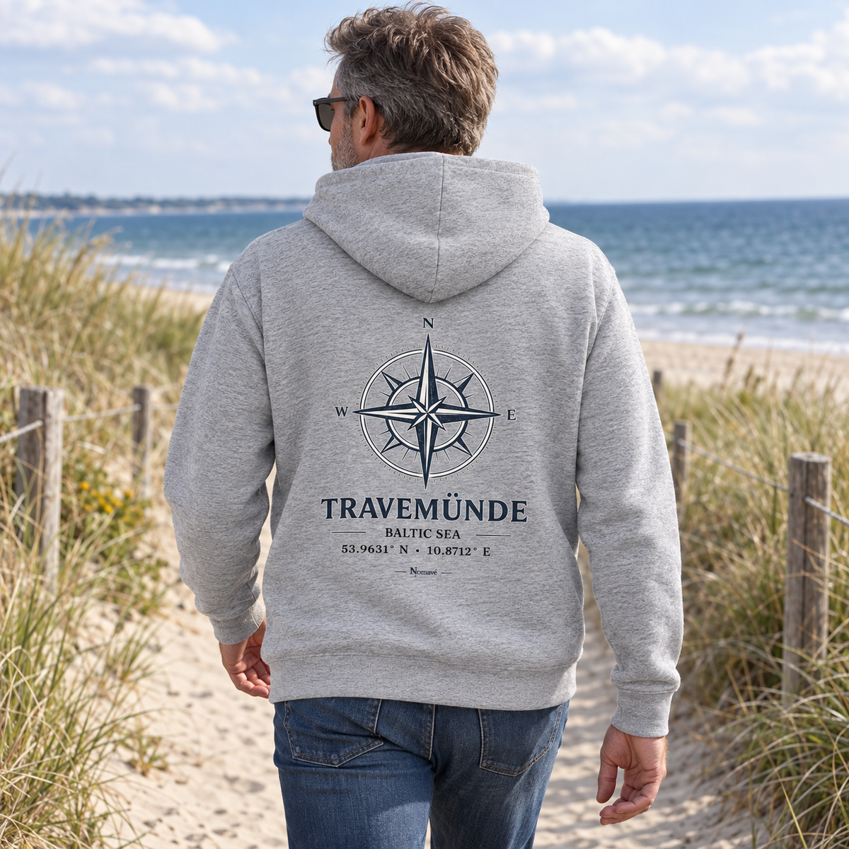 Mann im Heather-Grey Travemünde Windrose Bio-Hoodie am Ostsee-Dünenweg