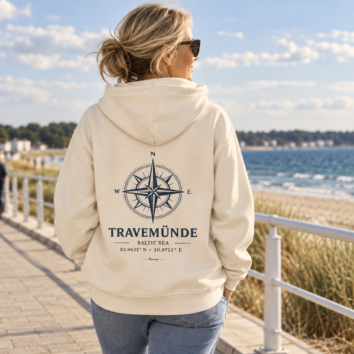 Frau im Natural-Raw Travemünde Windrose Bio-Hoodie an der Ostsee-Promenade