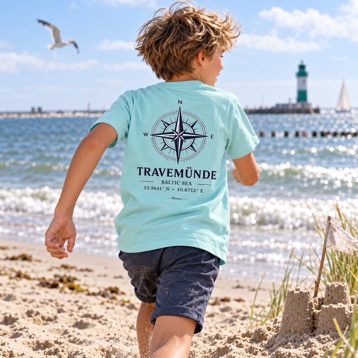 Kind mit Travemünde Windrose Bio T-Shirt in Caribbean Blue am Strand